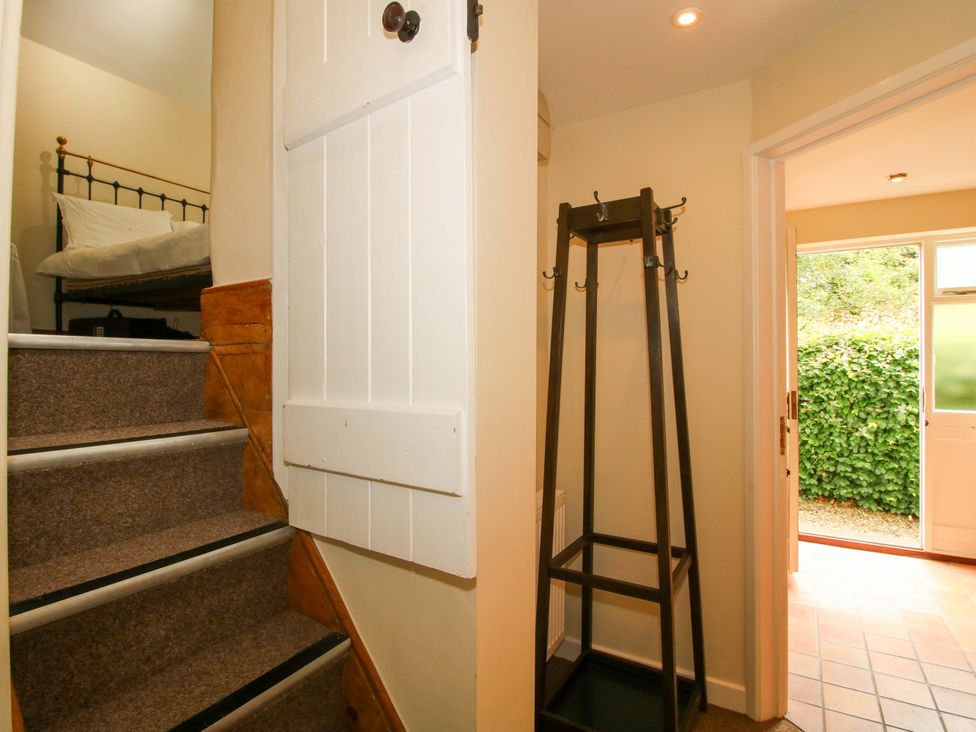 A hallway with a staircase and clothes rack at Kwerky Cottage