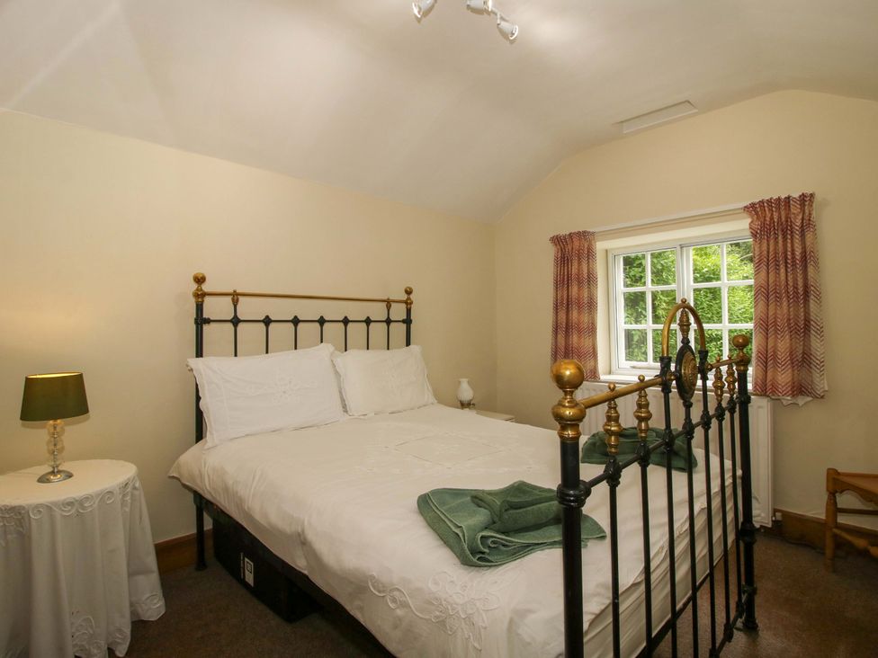 A bedroom with a bed and nightstand at Kwerky Cottage 