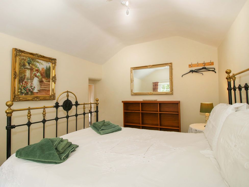 A bedroom with a bed and mirror at Kwerky Cottage