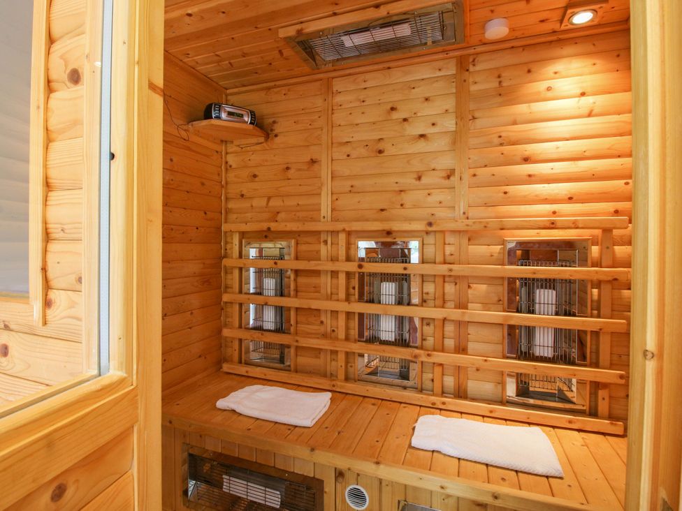 A sauna with wooden benches and heat lamps at Kwerky Cottage