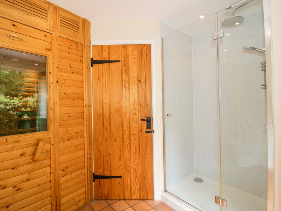 A bathroom with a sauna and a glass shower at Kwerky Cottage