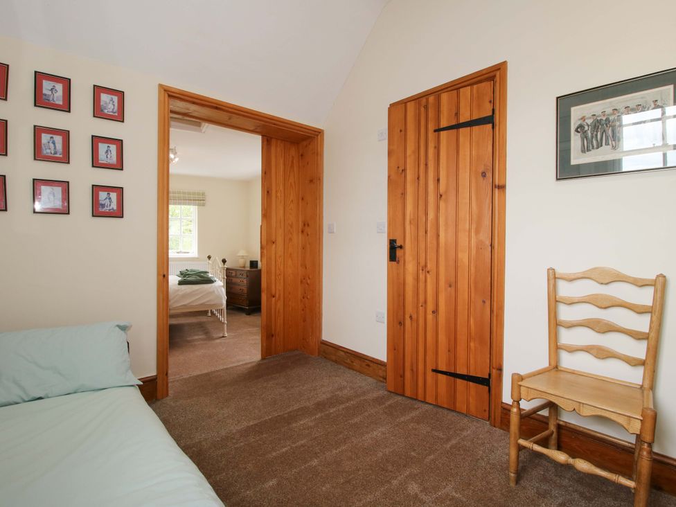 A bedroom with a bed and chair at Kwerky Cottage