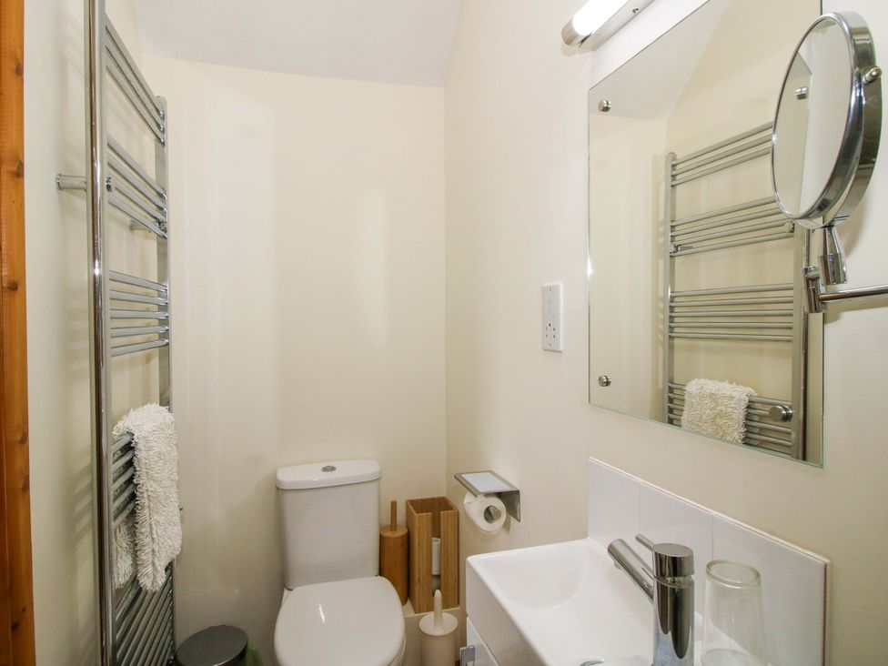 A bathroom with a toilet, sink, and mirror at Kwerky Cottage