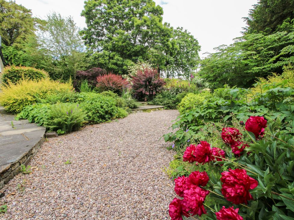 A garden with a gravel path and red peonies at Kwerky Cottage Lydbury North