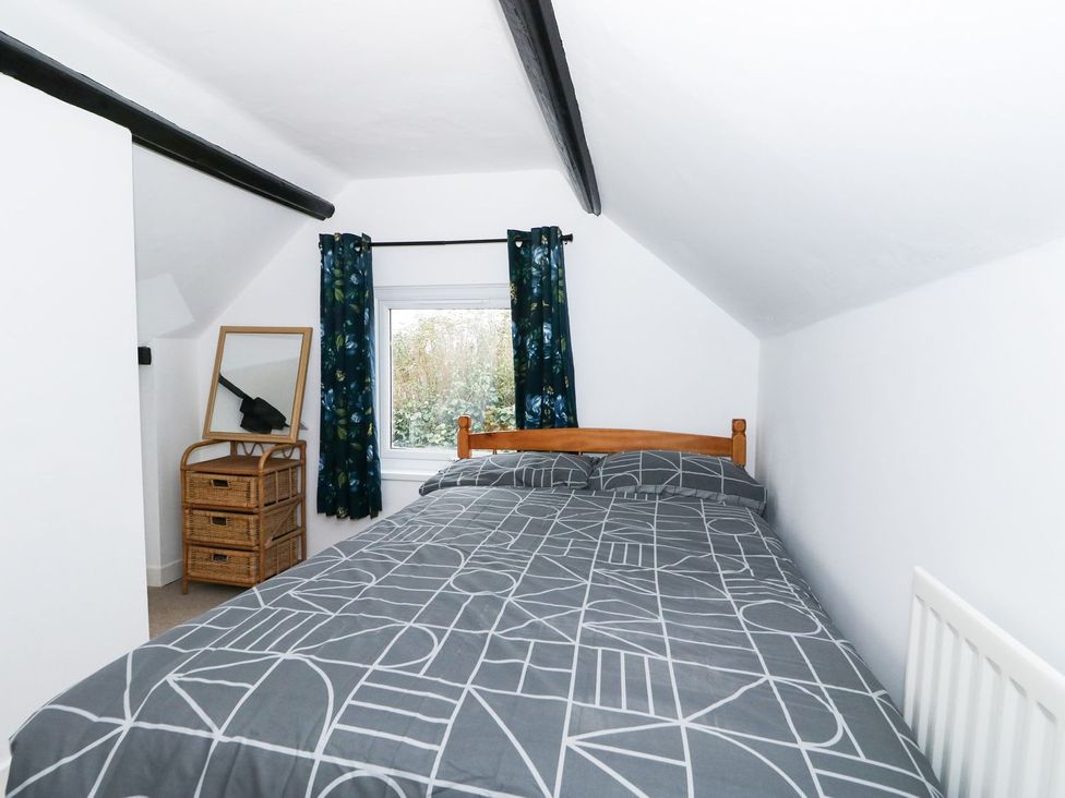 A bedroom with a bed and mirror at Oar Cottage in Mablethorpe