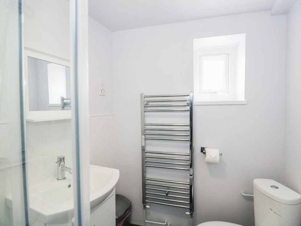A bathroom with a sink, toilet, mirror and towel rail at Oar Cottage in Mablethorpe
