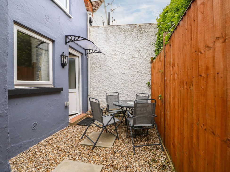 An outdoor seating area with a round table and chairs at Oar Cottage in Mablethorpe