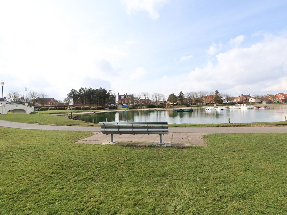 An outdoor area with a bench by a lake at Oar Cottage in Mablethorpe
