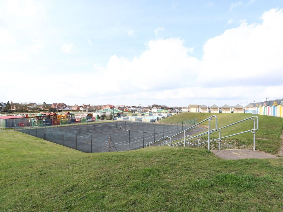 An outdoor area with a tennis court and beach huts at Oar Cottage Mablethorpe