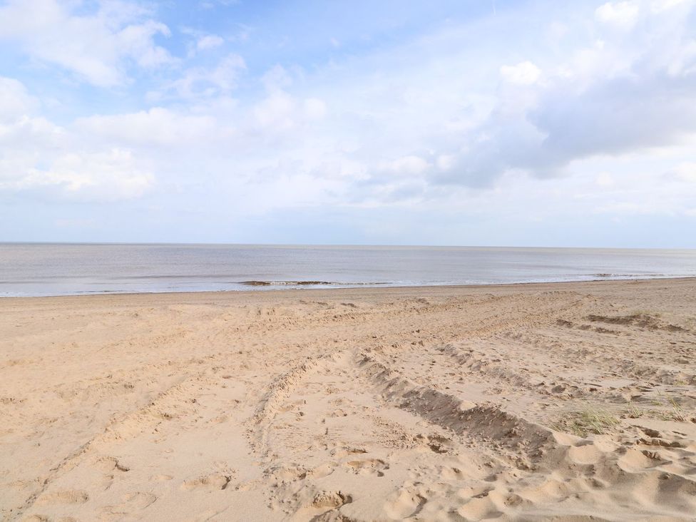 An empty beach with sand and calm sea at Oar Cottage in Mablethorpe