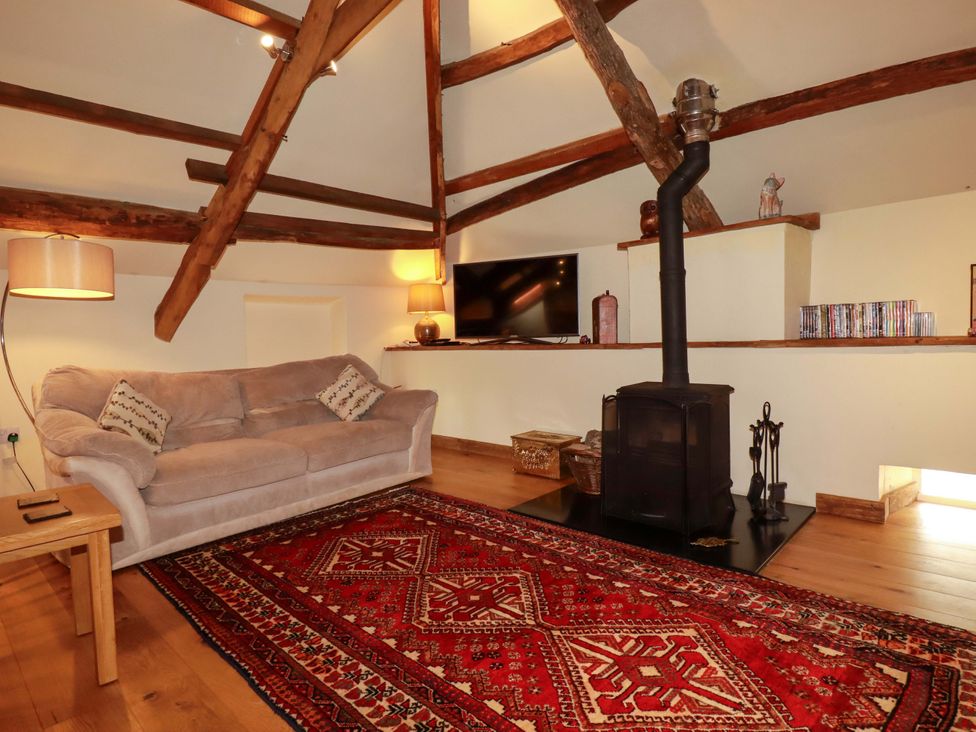 A living room with a sofa, television, and stove at The Water Mill at Boyton Mill, Launceston