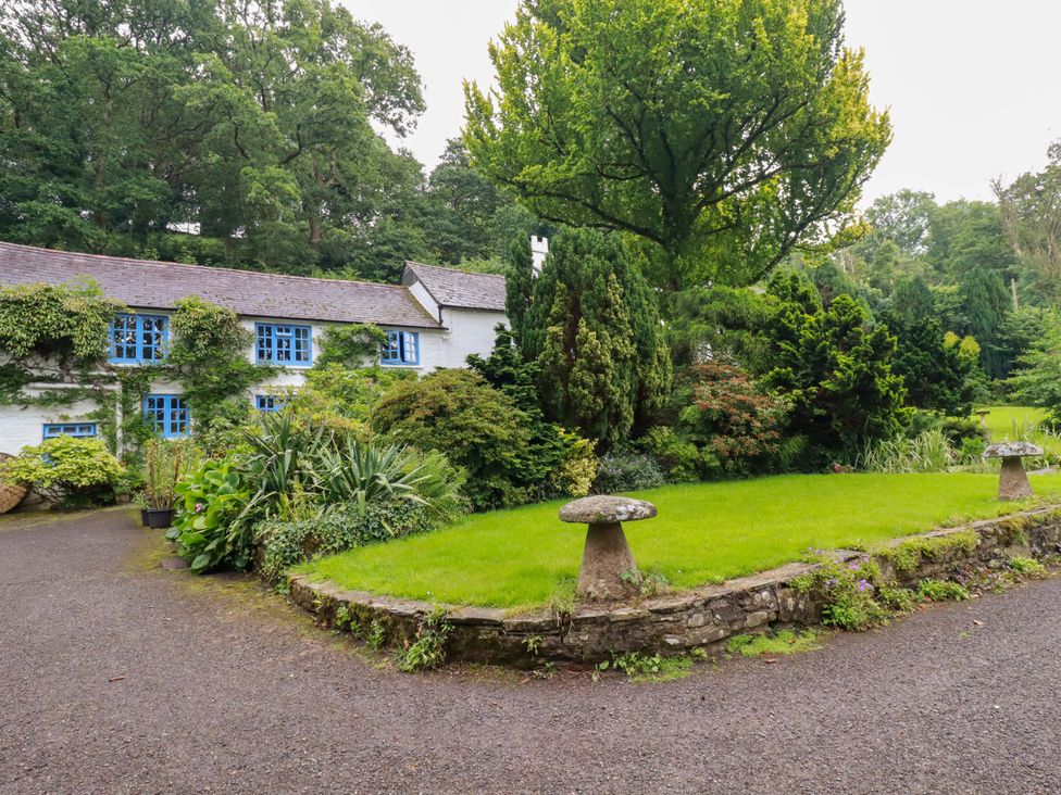 A garden with a building and trees at The Water Mill at Boyton Mill Launceston