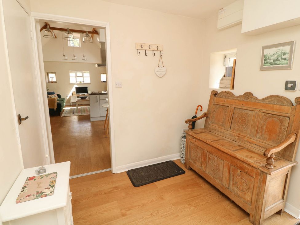 A hallway with a bench and coat hooks at Wheelwrights Cottage in Corby Glen