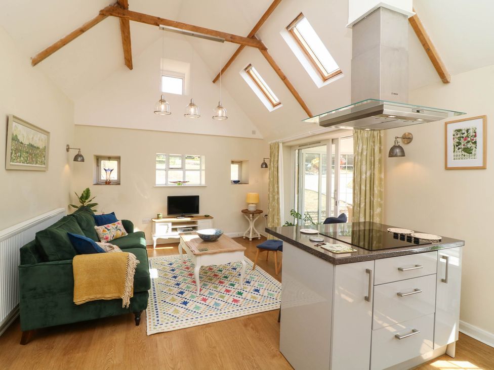 A living room with a sofa and kitchen island at Wheelwrights Cottage in Corby Glen