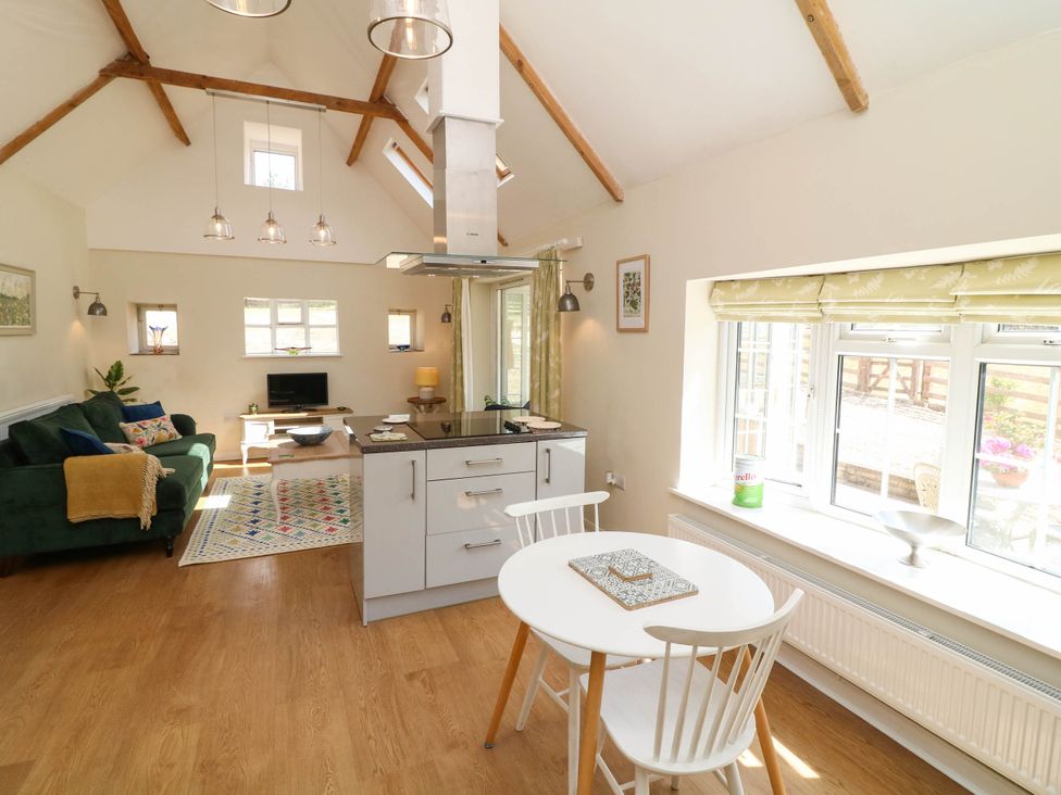 An open plan living area with a dining table and kitchen at Wheelwrights Cottage in Corby Glen