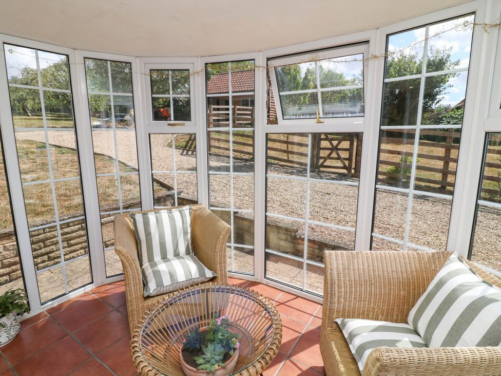 A conservatory with seating and a table at Wheelwrights Cottage in Corby Glen