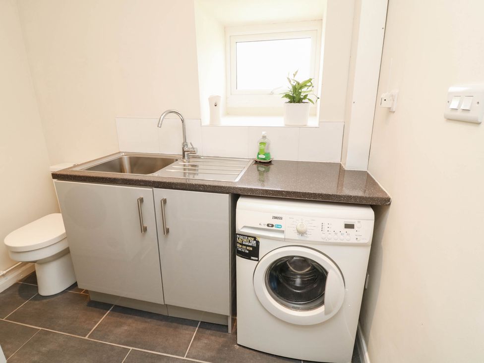 A laundry room with a sink and washing machine at Wheelwrights Cottage in Corby Glen
