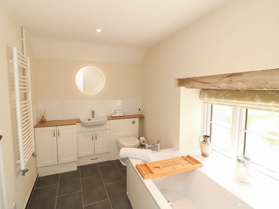 A bathroom with a bathtub and sink at Wheelwrights Cottage in Corby Glen