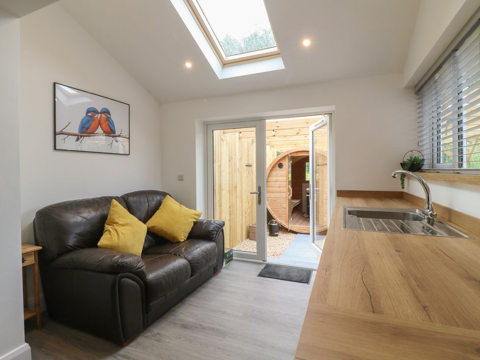 A snug with a sofa and a door leading outside at The Kingfisher Falls in Melton Mowbray