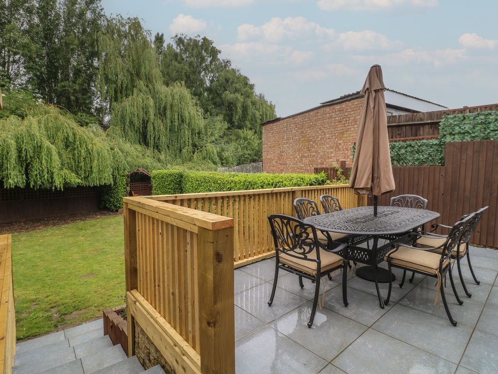 A garden with a wooden table and chairs at The Kingfisher Falls in Melton Mowbray