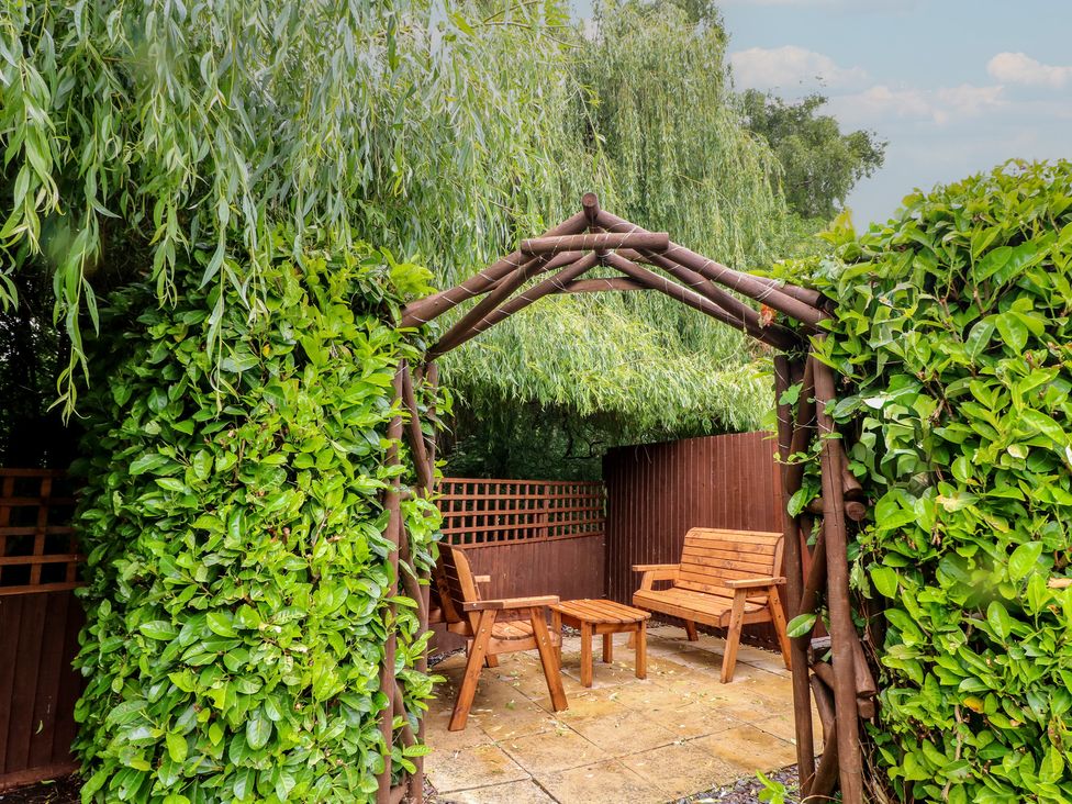 A garden with wooden benches and a table at The Kingfisher Falls in Melton Mowbray