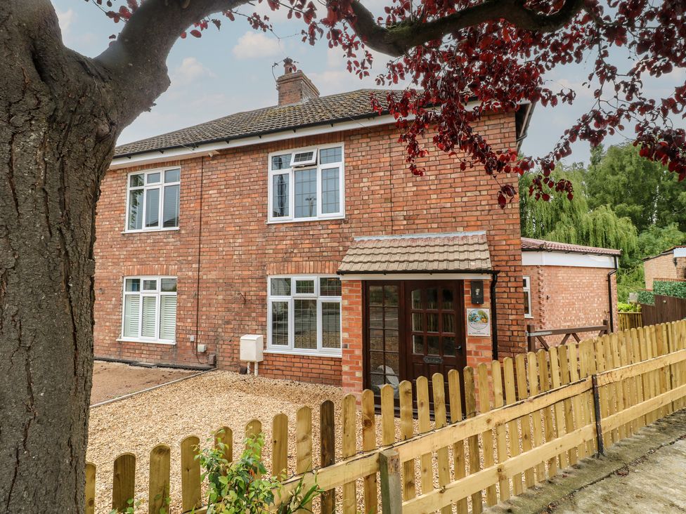 A brick house with windows and a front door surrounded by fence at The Kingfisher Falls in Melton Mowbray