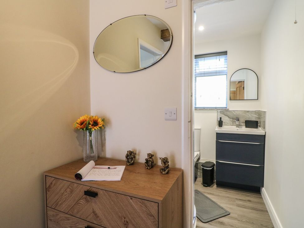 A hallway leading to a bathroom with a sink and toilet at The Kingfisher Falls in Melton Mowbray