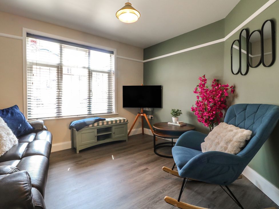 A living room with a sofa, chair, coffee table, and television at The Kingfisher Falls in Melton Mowbray