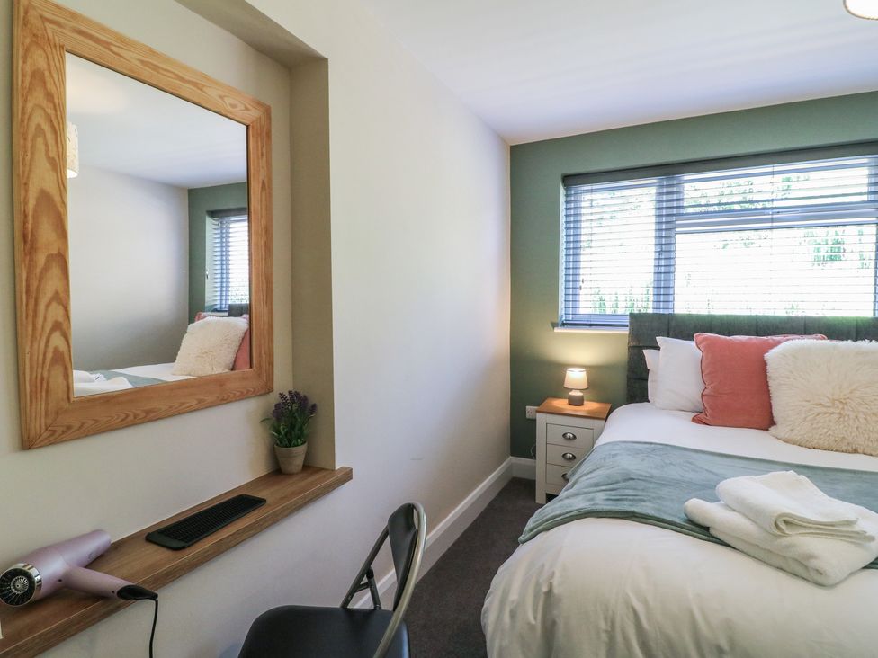 A bedroom with a bed and mirror at The Kingfisher Falls in Melton Mowbray