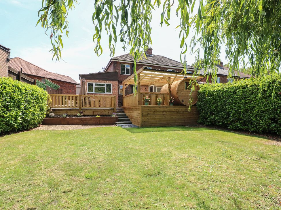 A garden with a wooden deck and steps at The Kingfisher Falls in Melton Mowbray