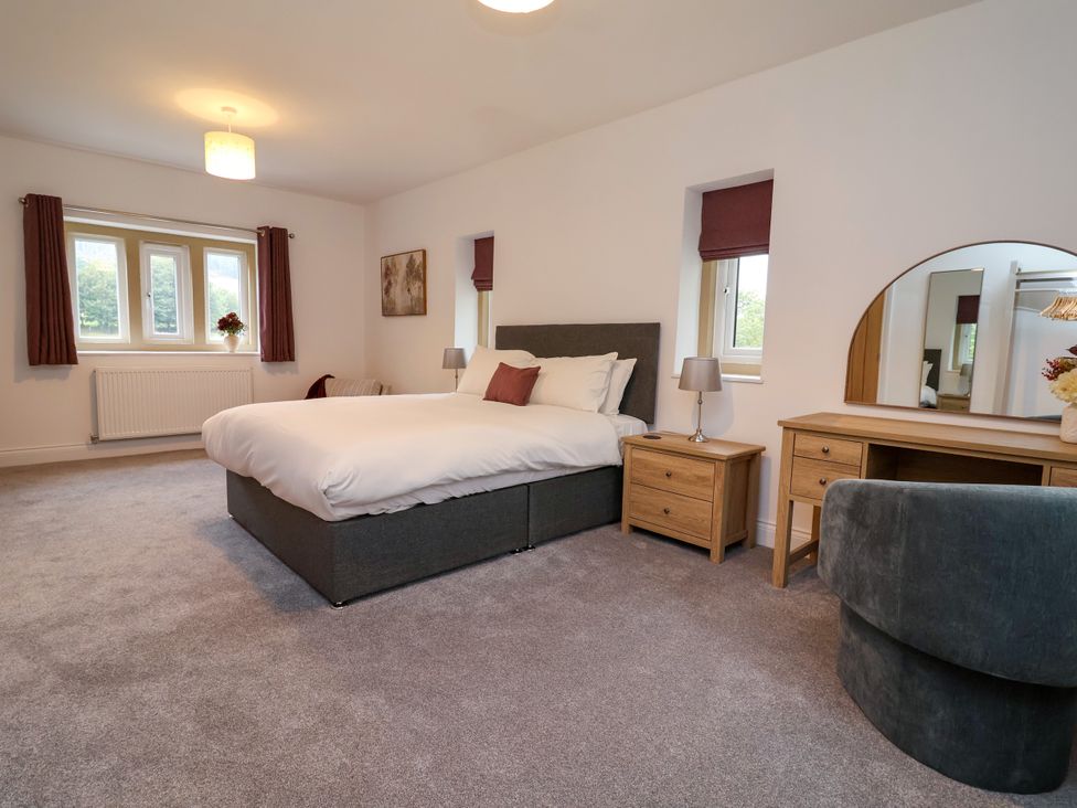 A bedroom with a bed, nightstand, lamp, and a mirror at Greenfield Manor near Greenfield