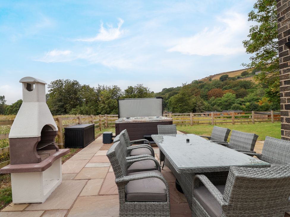 An outdoor area with a dining table and hot tub at Greenfield Manor near Greenfield