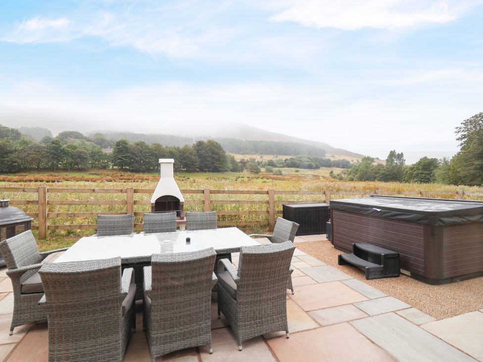 An outdoor dining area with a hot tub and grill at Greenfield Manor near Greenfield