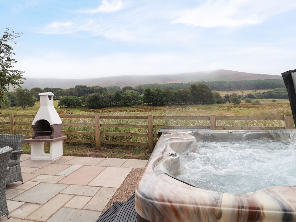 An outdoor area with a hot tub and fireplace at Greenfield Manor near Greenfield