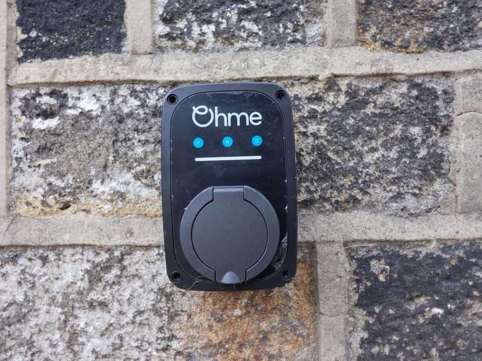 An electric vehicle charger mounted on a stone wall at Greenfield Manor near Greenfield