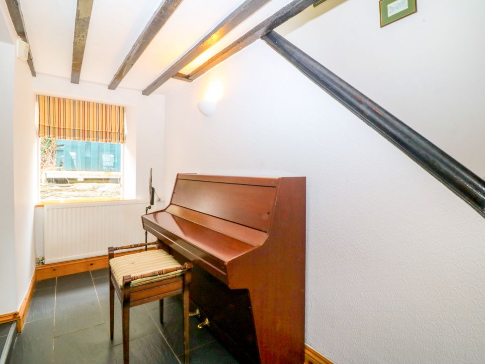 A hallway with a piano and chair at Ty Mawr Criccieth