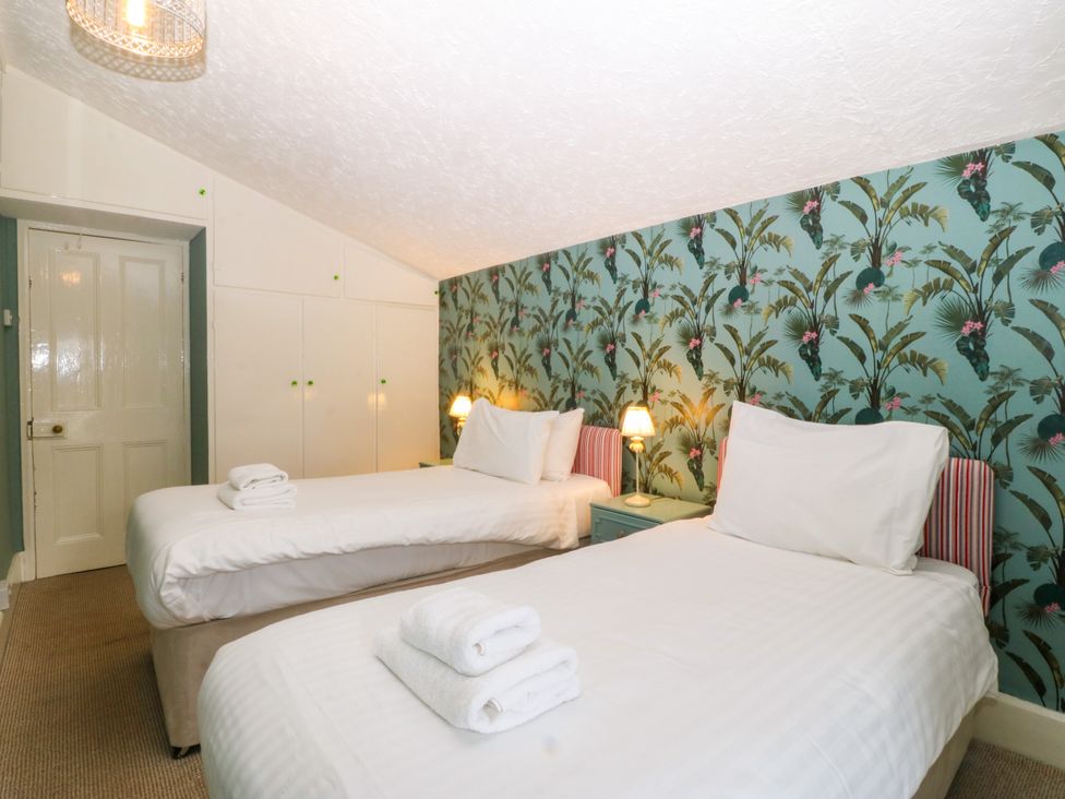 A bedroom with two single beds and a wardrobe at Ty Mawr in Criccieth