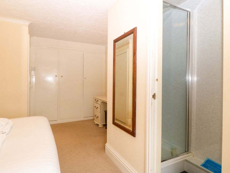 A bedroom with a bed, wardrobe, mirror, desk, and shower at Ty Mawr Criccieth