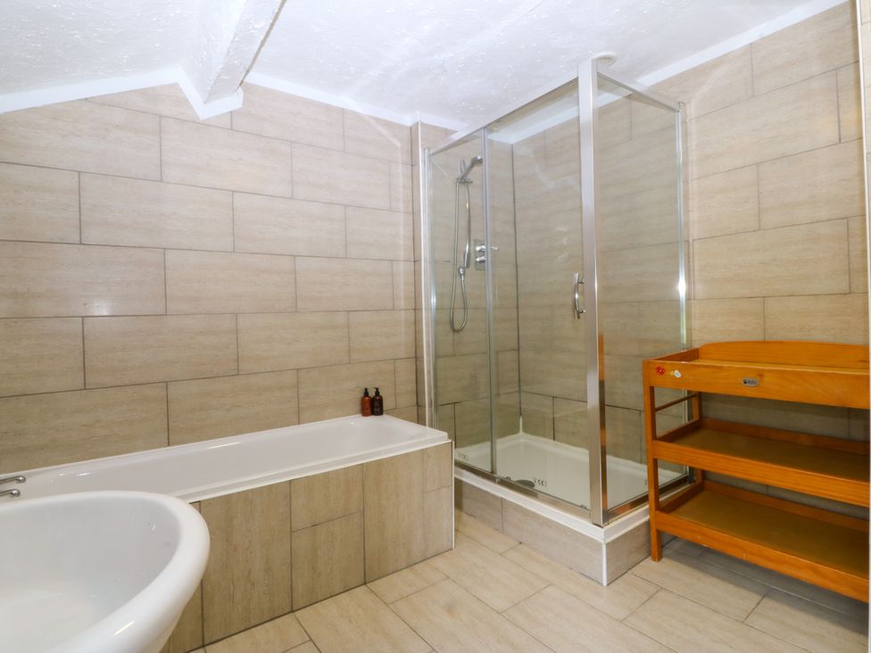 A bathroom with a bathtub and shower enclosure at Ty Mawr Criccieth