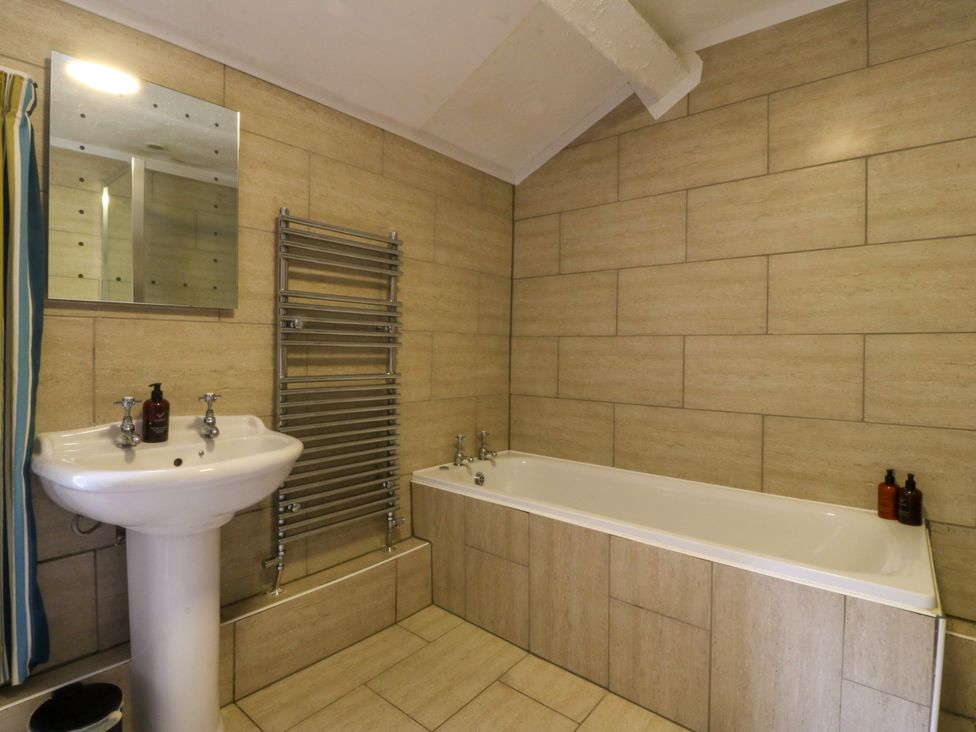 A bathroom with a sink, bathtub, and mirror at Ty Mawr, Criccieth