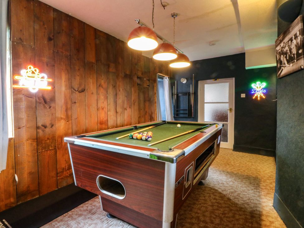 A game room with a pool table and neon signage at Ty Mawr in Criccieth