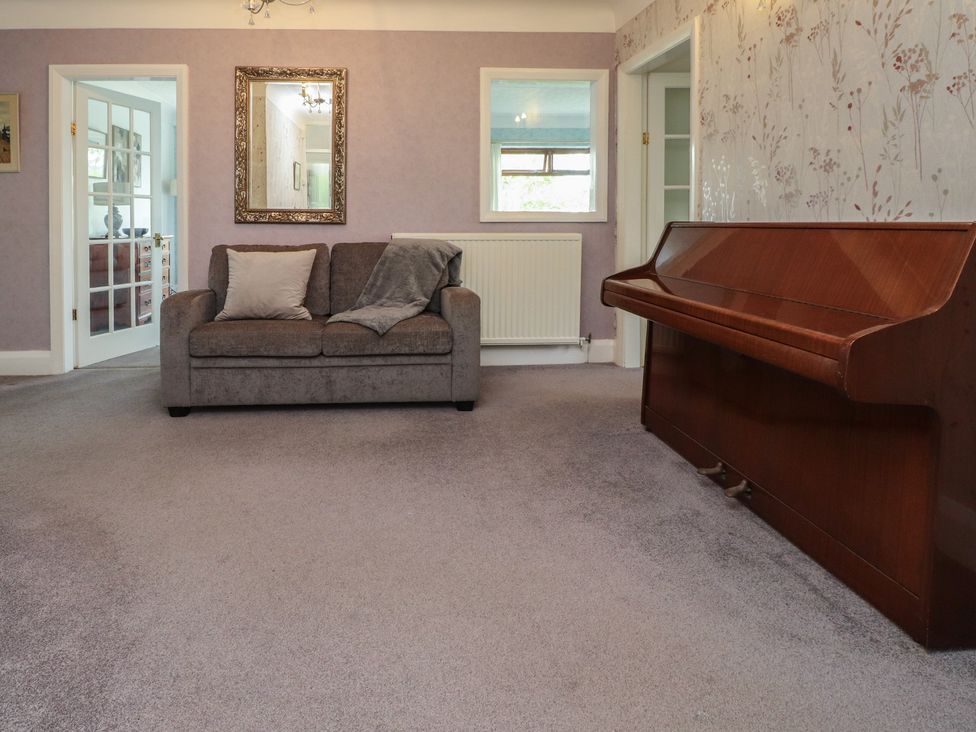 A living room with a sofa and piano at Nampara in Colwyn Bay