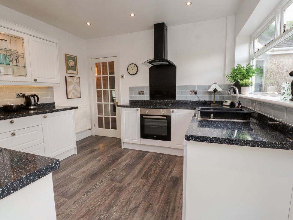 A kitchen with cabinets, counter, oven, sink, and kettle at Nampara in Colwyn Bay