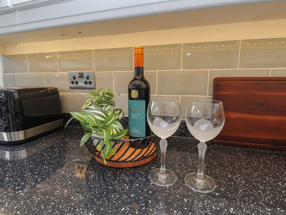 A kitchen countertop with a wine bottle and glasses at Nampara in Colwyn Bay