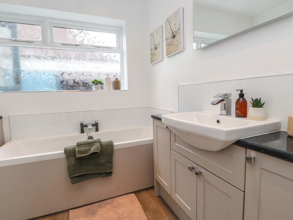 A bathroom with a bathtub and sink at Nampara in Colwyn Bay