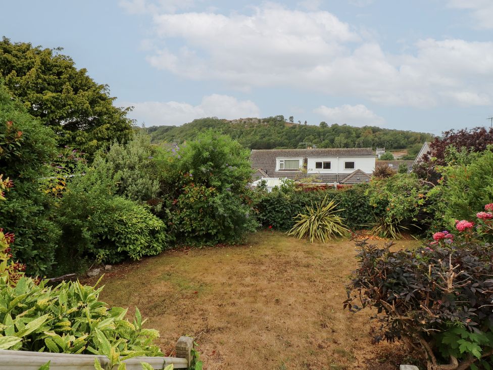 A garden with various plants and a view of the surrounding hills at Nampara, Colwyn Bay