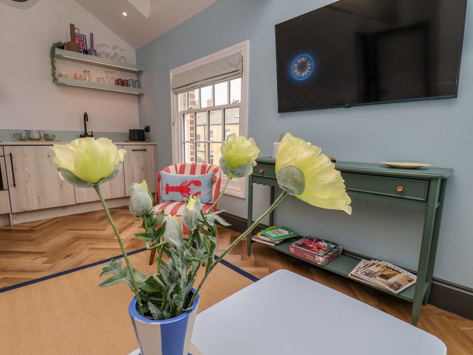 A living room with a flower vase and a tv at Apartment Blue in Whitby