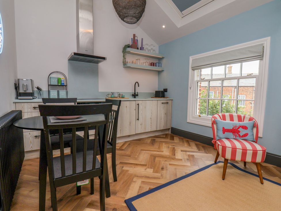 A kitchen featuring a table, chairs, and modern appliances at Apartment Blue in Whitby