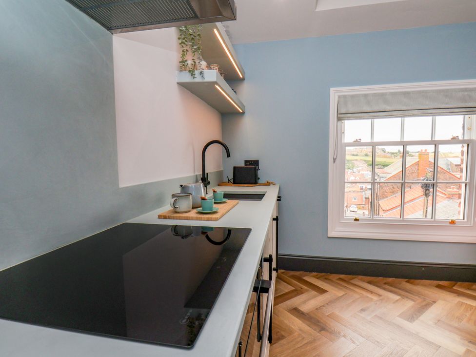 A kitchen with a cooking stove and shelves at Apartment Blue in Whitby