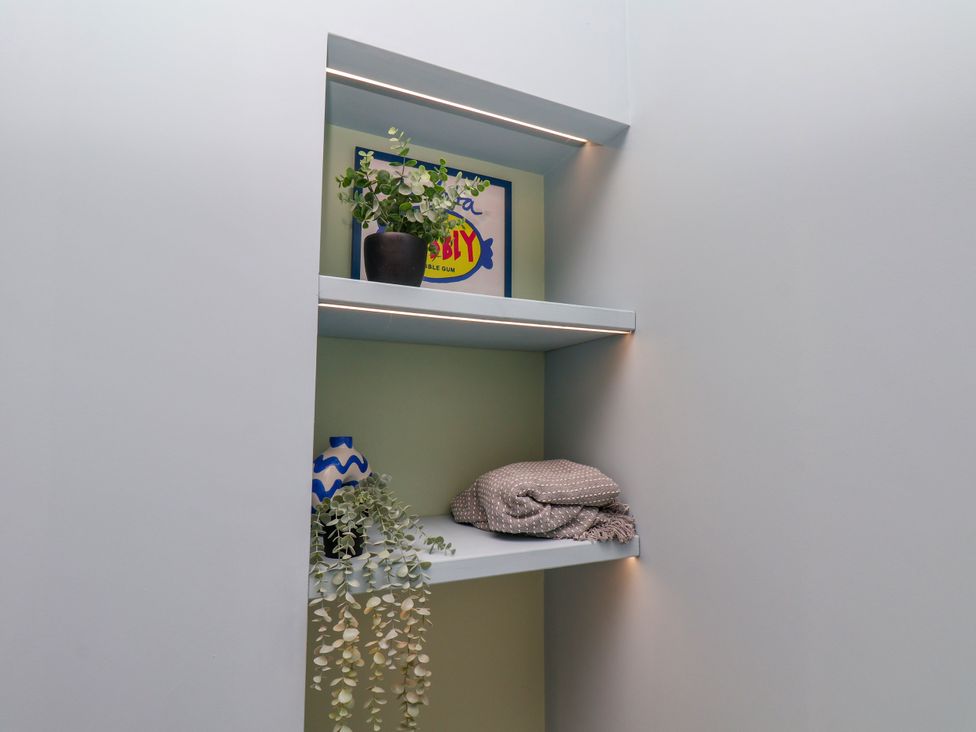 A nook with shelves containing a plant, picture, vase, and blanket at Apartment Blue in Whitby